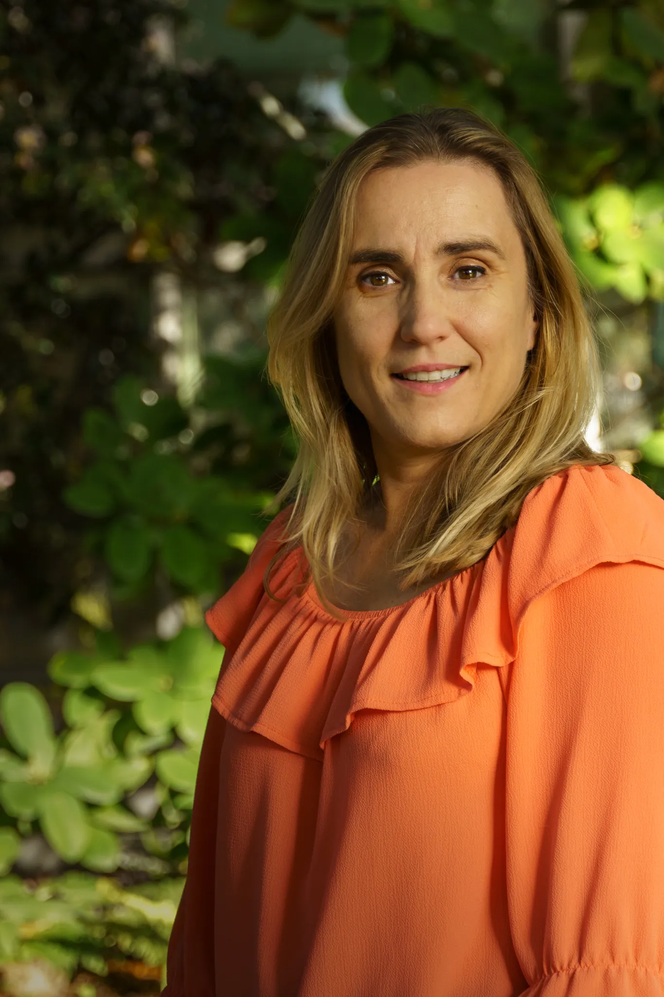 Portrait doux femme blonde sur fond de verdure.