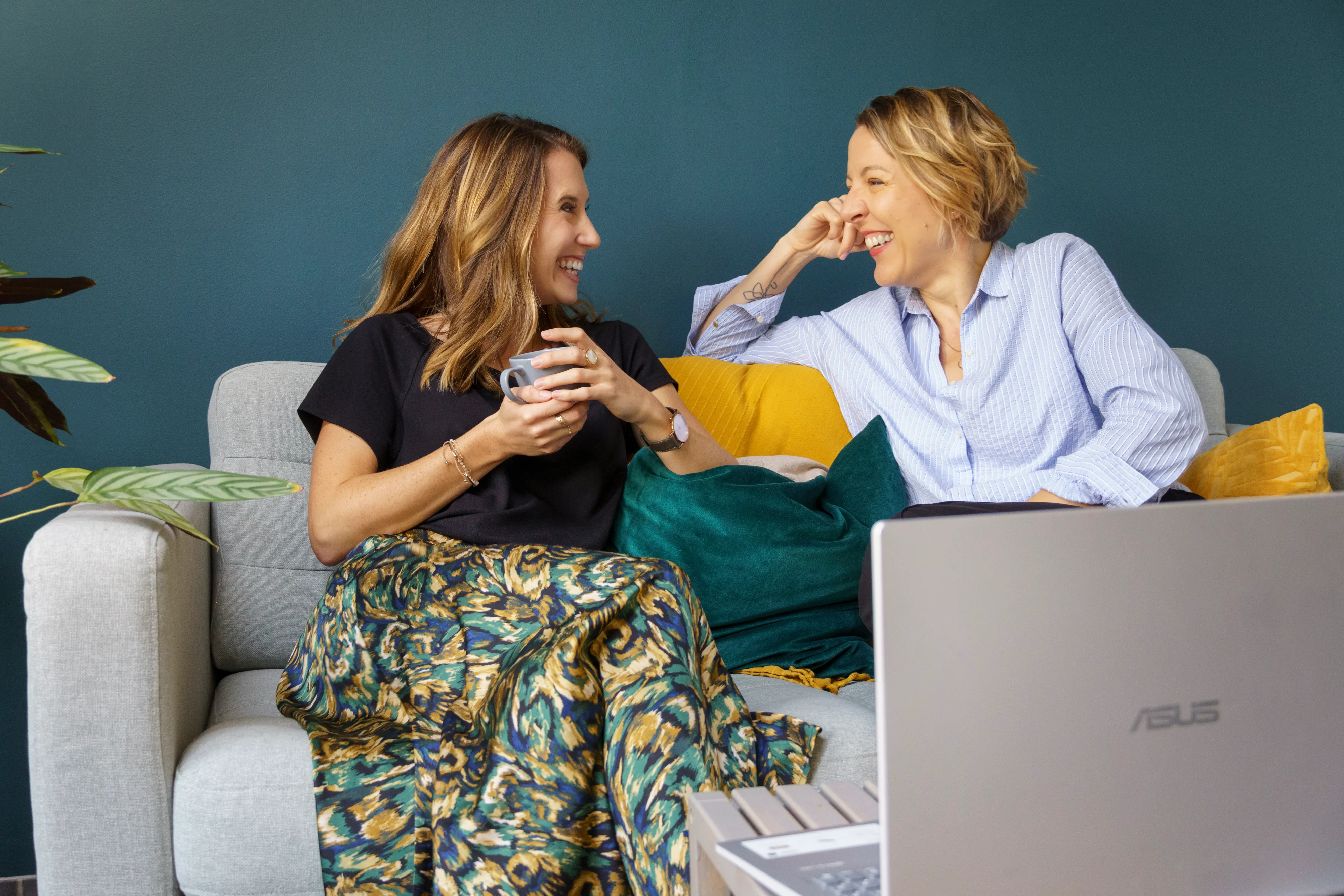 Collaboratrices échangeant et riant sur un canapé