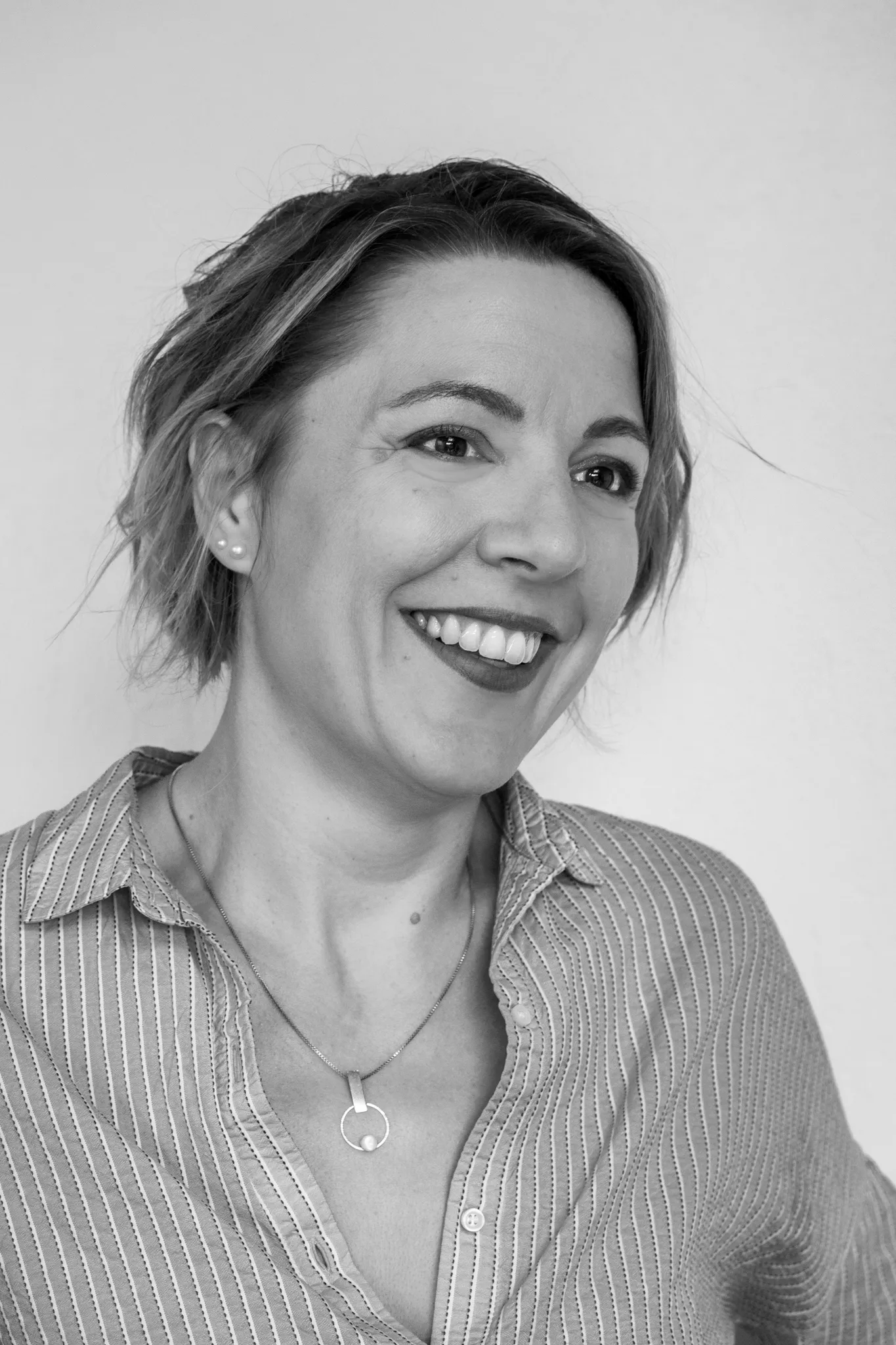 Portrait noir et blanc, femme au grand sourire et cheveux courts.