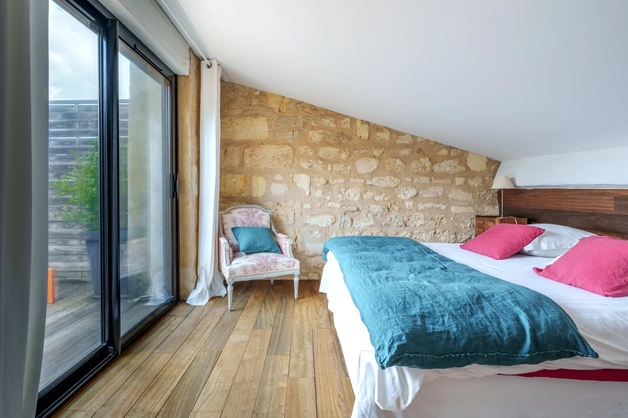 Lit double, pièce mur en pierre, parquet, baie vitrée