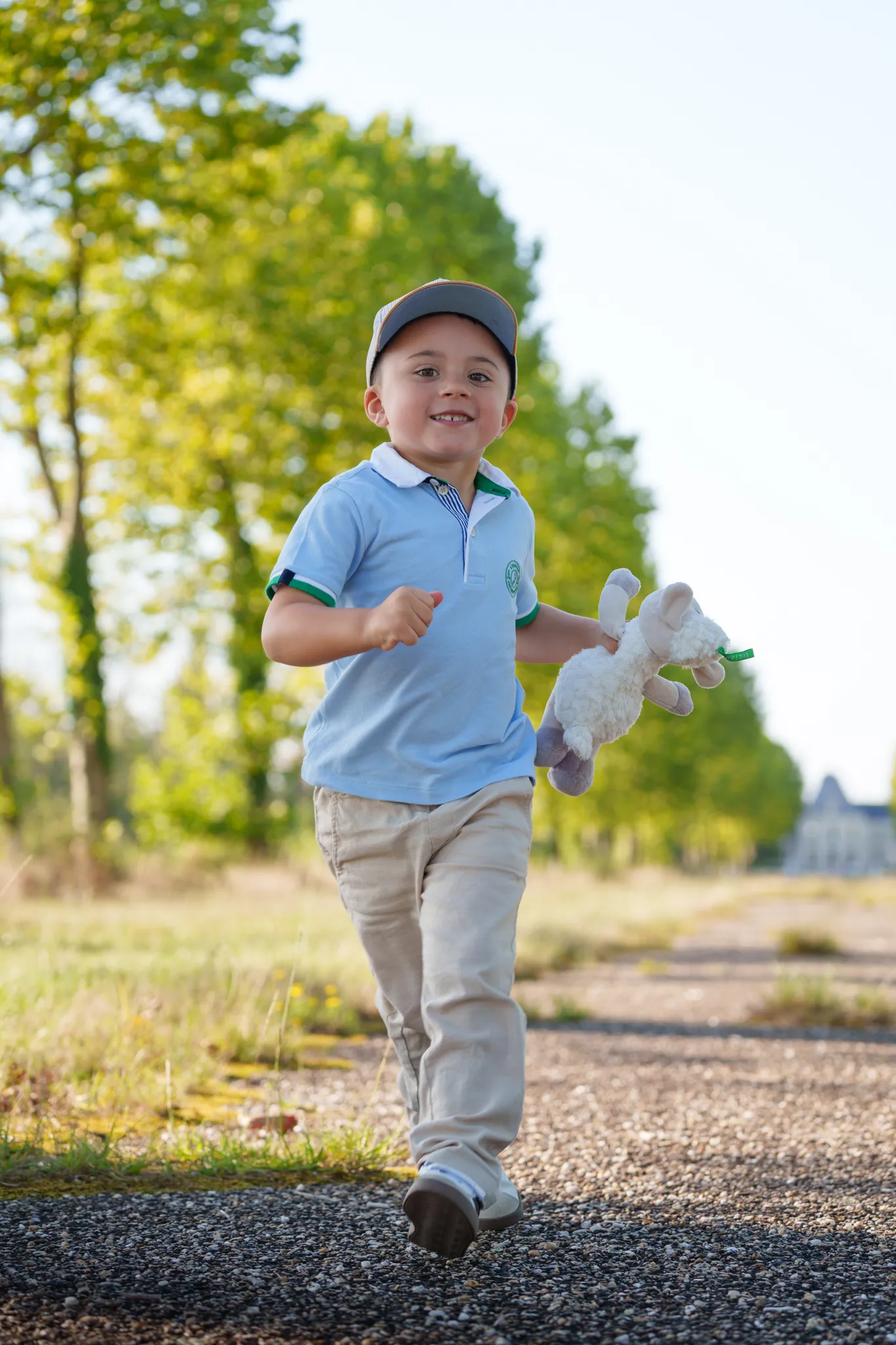 Petit garçon souriant qui court, avec son doudou à la main.