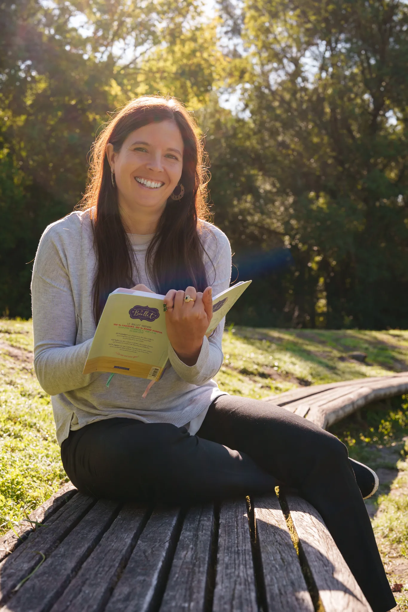Coach seo qui prend note sur un carnet, assise sur un banc dans un parc.