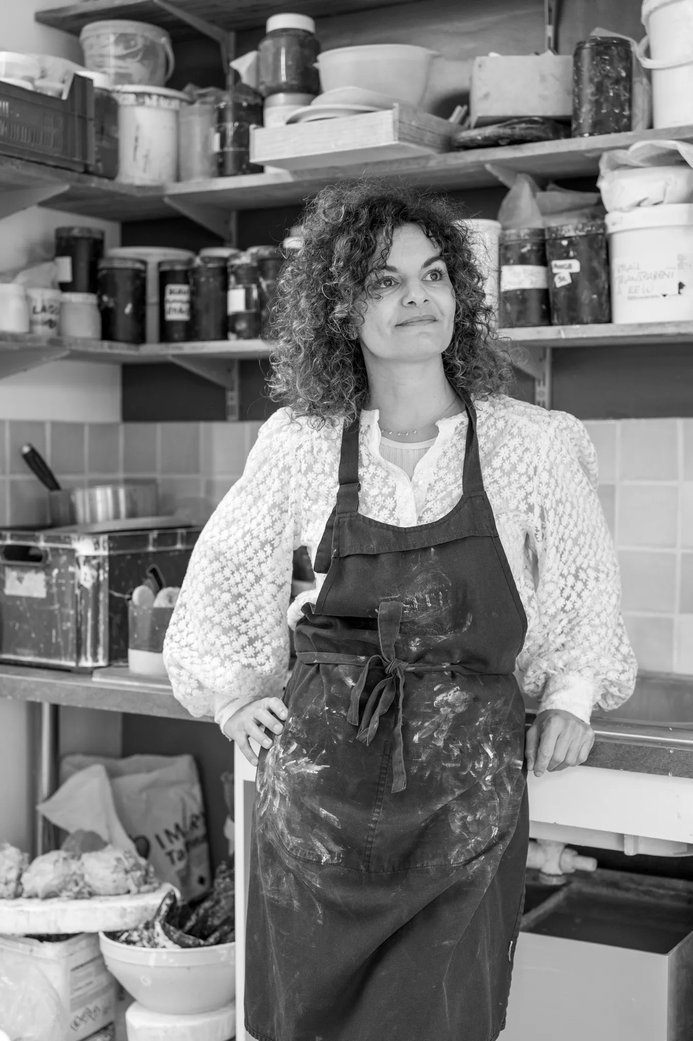 Portrait en noir et blanc d'une céramiste en tablier de travail.