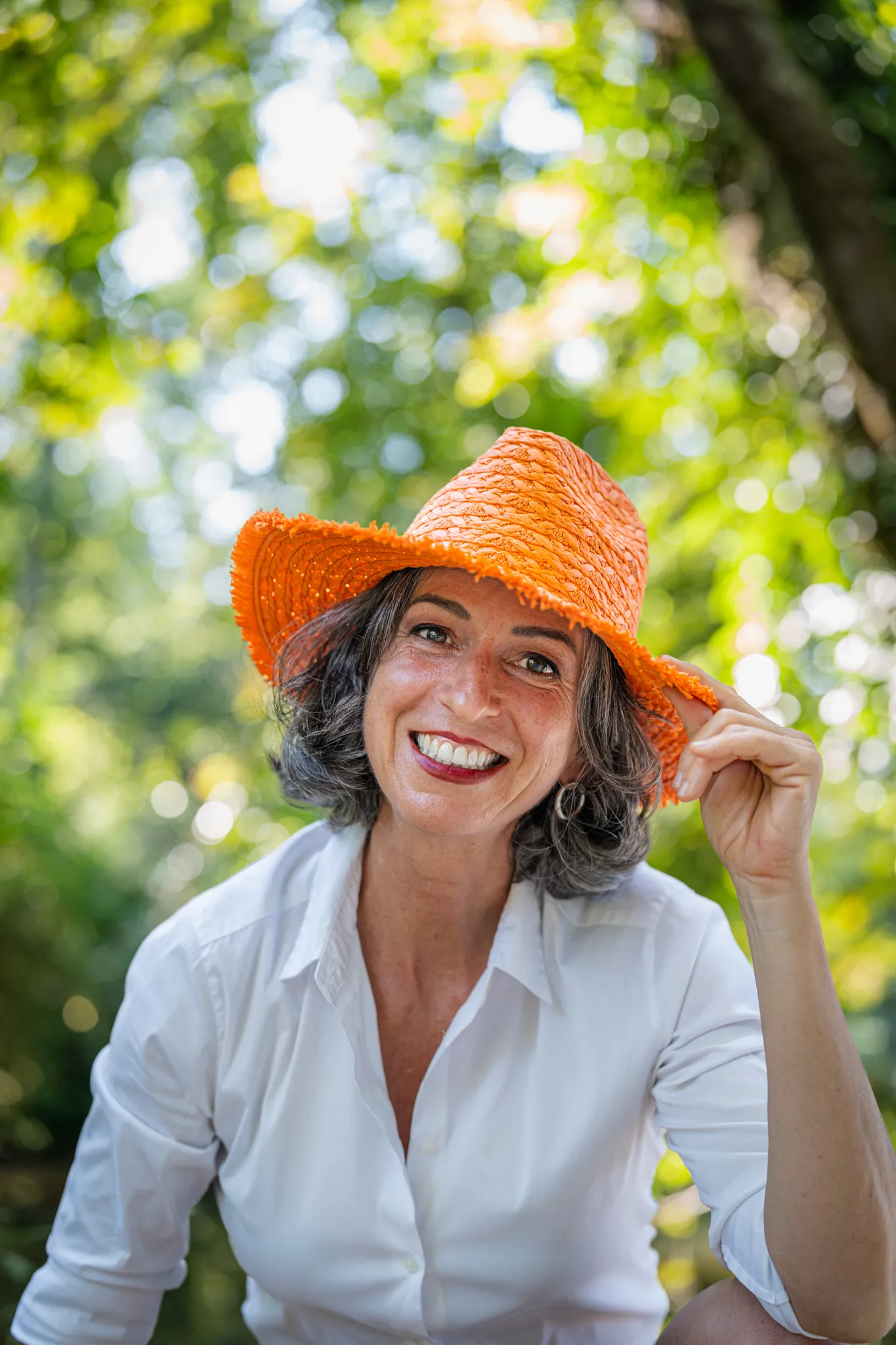 Femme joyeuse portant un chapeau orange, en pleine nature.