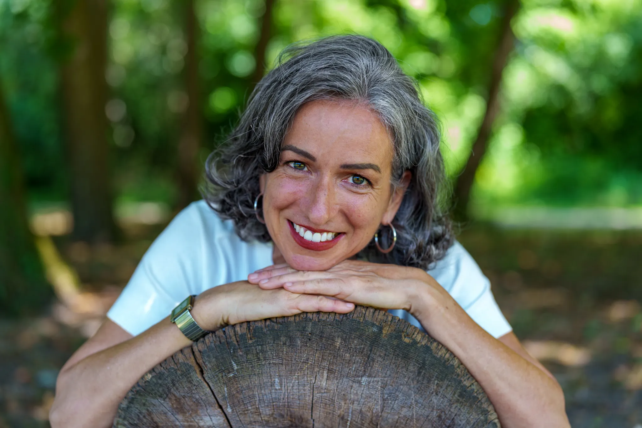 Femme appuyée sur une souche d'arbre, sourir chaleureux.