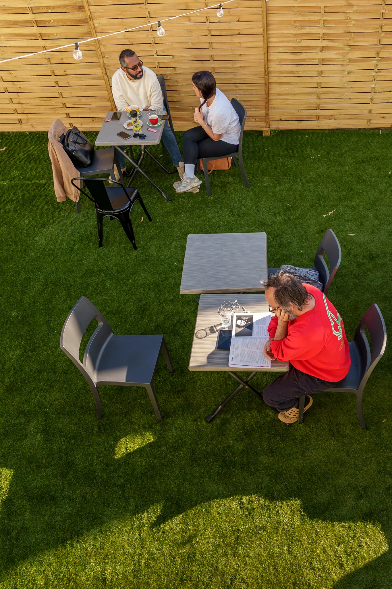 Vue d'une terrasse, avec un homme qui lit son journal.